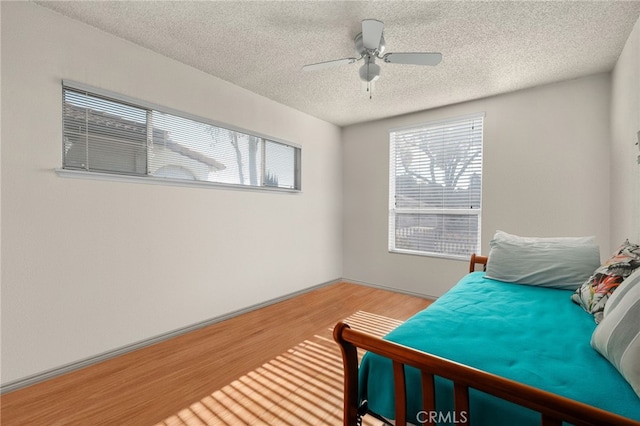 bedroom with a textured ceiling, ceiling fan, and hardwood / wood-style floors