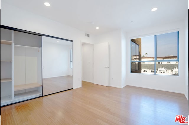 unfurnished bedroom with light hardwood / wood-style flooring and a closet