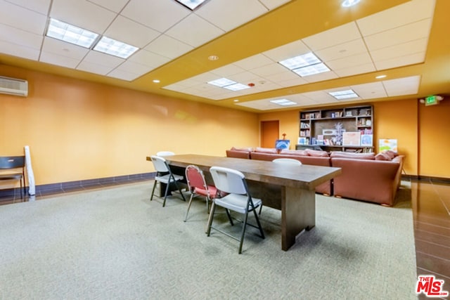 carpeted home office with an AC wall unit and a drop ceiling