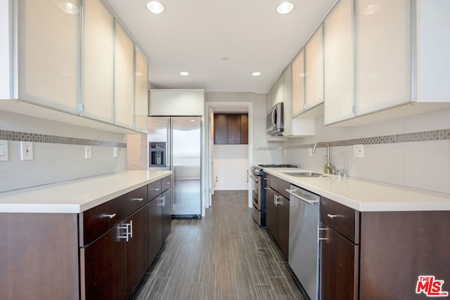 kitchen featuring white cabinetry, stainless steel appliances, backsplash, dark brown cabinets, and sink