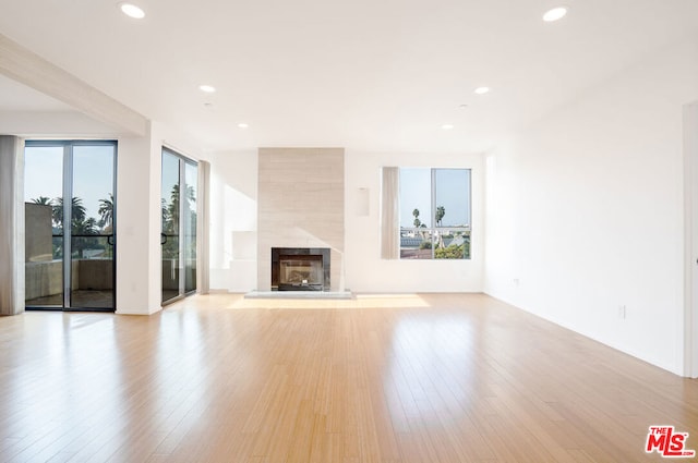 unfurnished living room with light wood-type flooring and a tile fireplace