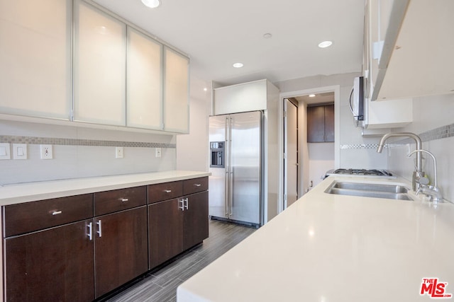 kitchen featuring backsplash, sink, high end fridge, white cabinets, and dark brown cabinets