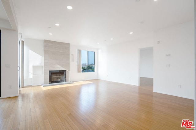 unfurnished living room featuring light hardwood / wood-style flooring and a tiled fireplace