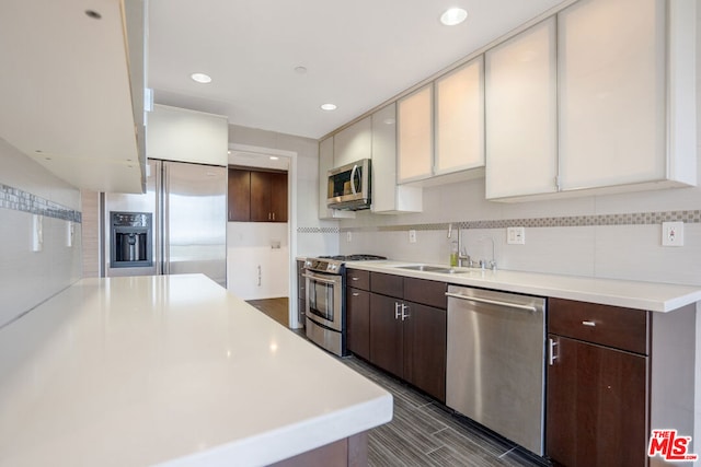 kitchen with decorative backsplash, sink, dark brown cabinetry, appliances with stainless steel finishes, and white cabinets