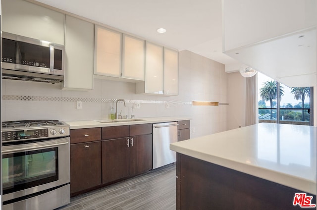 kitchen featuring white cabinetry, appliances with stainless steel finishes, tasteful backsplash, dark brown cabinets, and sink