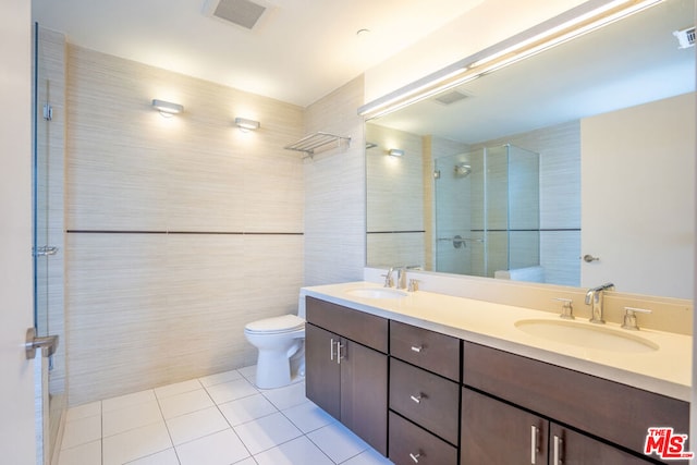 bathroom featuring toilet, tile patterned flooring, a shower with door, and vanity