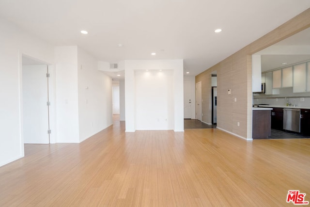 unfurnished living room featuring sink and light hardwood / wood-style floors