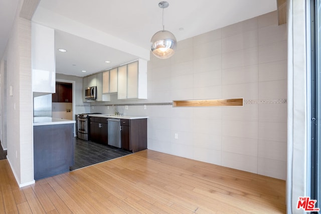 kitchen featuring wood-type flooring, white cabinetry, stainless steel appliances, sink, and dark brown cabinets