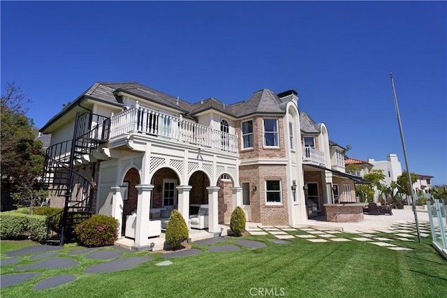 view of front of property featuring a patio area, a balcony, and a front yard