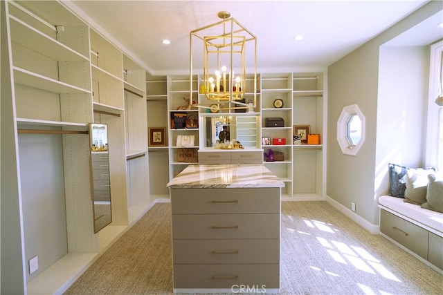 walk in closet featuring light colored carpet and an inviting chandelier