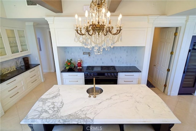 kitchen with a center island with sink, an inviting chandelier, and black range oven