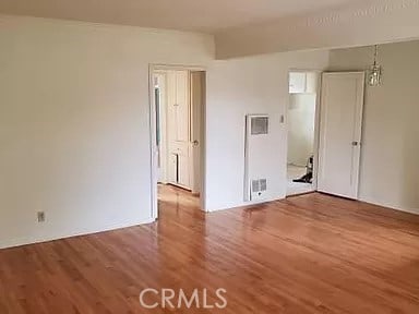 empty room with hardwood / wood-style floors and a notable chandelier