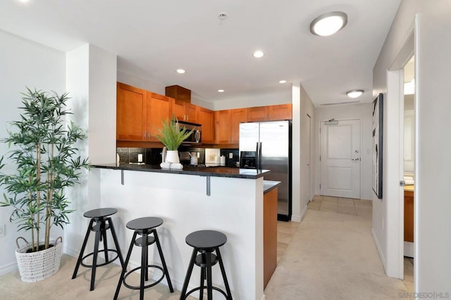 kitchen featuring decorative backsplash, a breakfast bar, kitchen peninsula, and stainless steel appliances