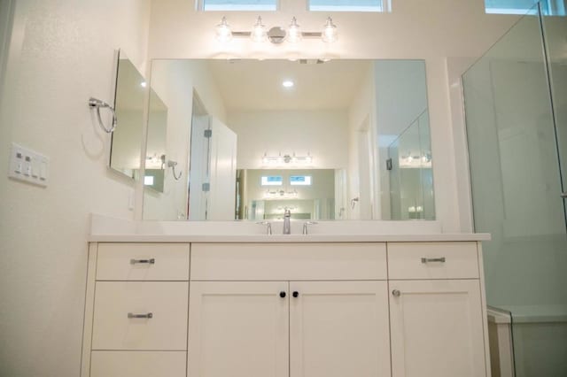 bathroom with a shower with shower door and vanity