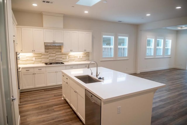 kitchen featuring stainless steel dishwasher, a kitchen island with sink, a skylight, and white cabinetry