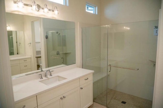 bathroom featuring toilet, vanity, and a shower with door