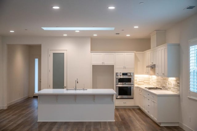 kitchen featuring dark hardwood / wood-style floors, a center island with sink, sink, stainless steel appliances, and white cabinets