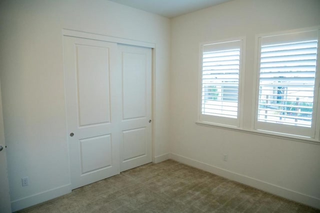 unfurnished bedroom with a closet and light colored carpet