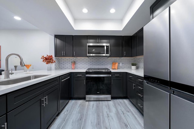 kitchen featuring stainless steel appliances, decorative backsplash, light hardwood / wood-style floors, and sink