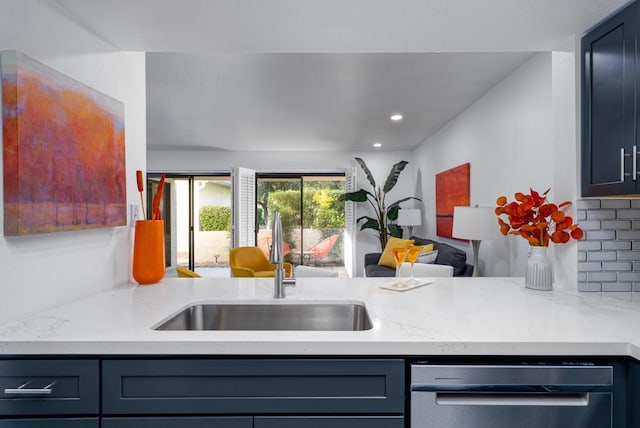 kitchen featuring light stone countertops, sink, kitchen peninsula, and tasteful backsplash