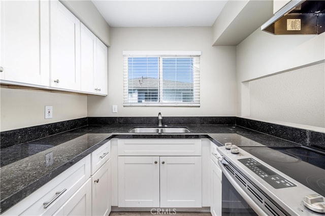 kitchen featuring white cabinetry, sink, stainless steel range with electric cooktop, and dark stone counters