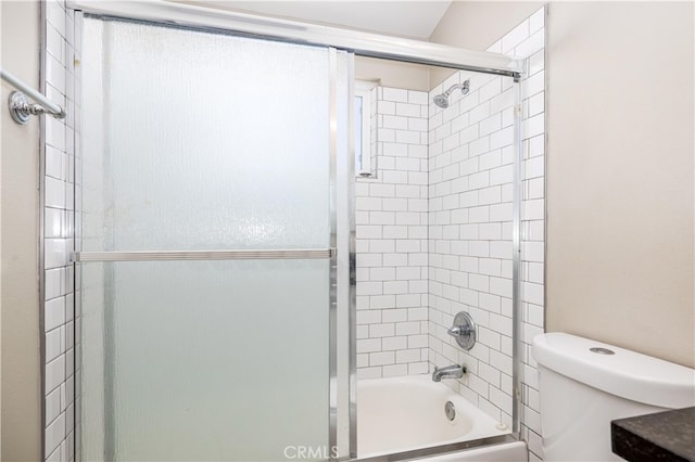 bathroom with toilet and shower / bath combination with glass door