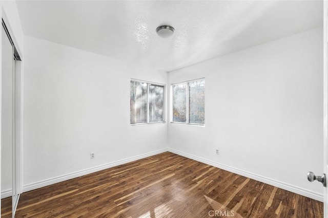 empty room featuring a textured ceiling and dark wood-type flooring