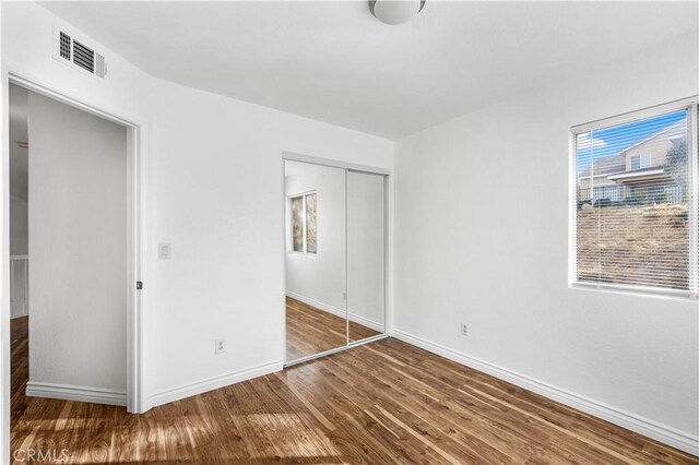 unfurnished bedroom with dark hardwood / wood-style floors and a closet