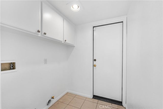 clothes washing area featuring light tile patterned floors, washer hookup, and cabinets