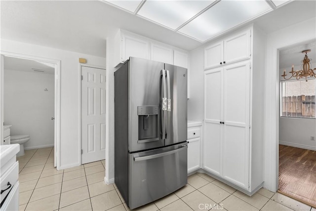 kitchen featuring stainless steel fridge with ice dispenser, light tile patterned flooring, and white cabinets