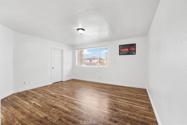 unfurnished room featuring a textured ceiling and dark hardwood / wood-style flooring