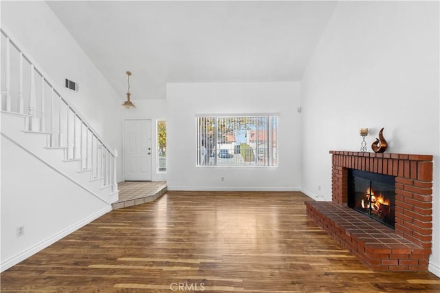 unfurnished living room with vaulted ceiling, a fireplace, and hardwood / wood-style flooring