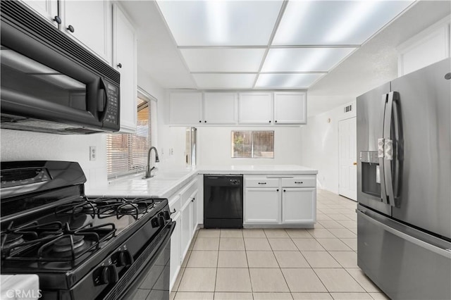 kitchen featuring light tile patterned floors, white cabinetry, sink, and black appliances