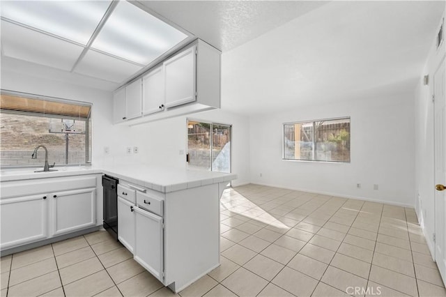 kitchen featuring light tile patterned floors, white cabinets, black dishwasher, and kitchen peninsula