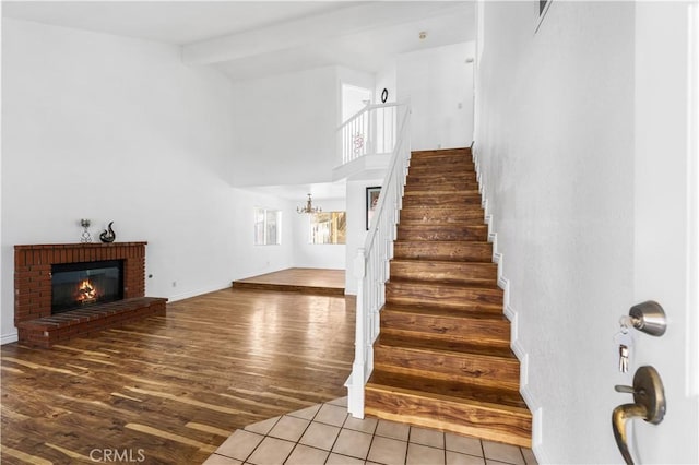 stairs featuring a brick fireplace, tile patterned floors, and lofted ceiling with beams