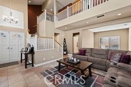 living room featuring tile patterned flooring, a towering ceiling, and a notable chandelier