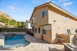 rear view of house featuring a patio area and a swimming pool with hot tub