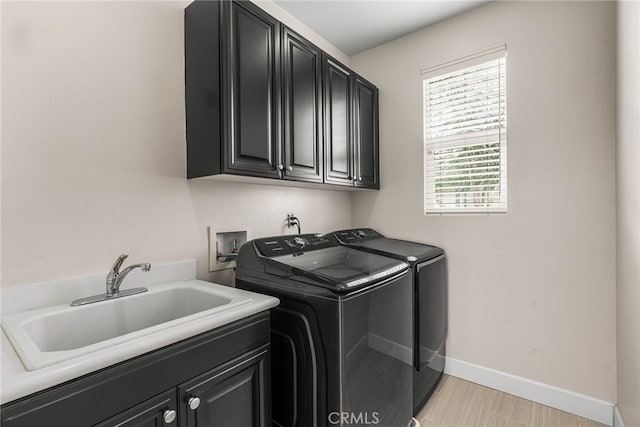 laundry area featuring cabinets, sink, a healthy amount of sunlight, and washing machine and clothes dryer