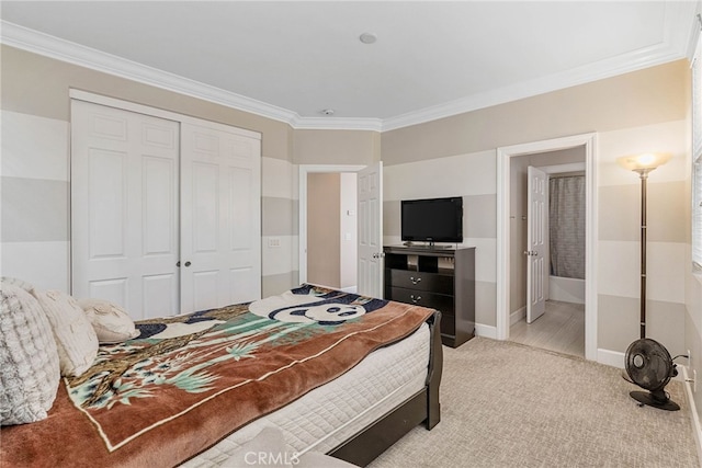 carpeted bedroom with ensuite bath, a closet, and ornamental molding