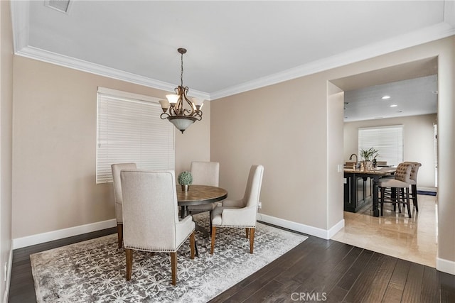 dining space with hardwood / wood-style floors, crown molding, and an inviting chandelier