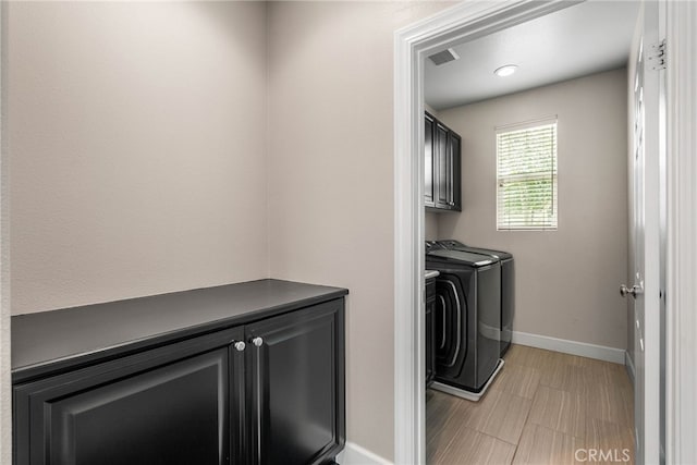 clothes washing area featuring cabinets and washing machine and dryer