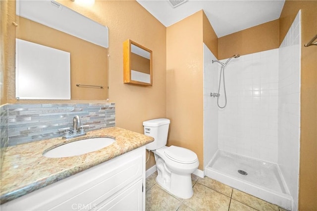 bathroom with toilet, tasteful backsplash, tiled shower, tile patterned floors, and vanity