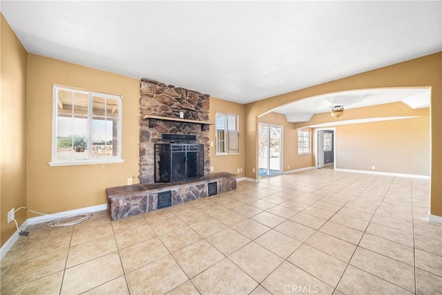 unfurnished living room with light tile patterned floors and a stone fireplace