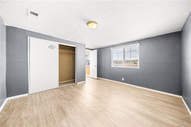 unfurnished bedroom with a closet, a textured ceiling, and light hardwood / wood-style floors