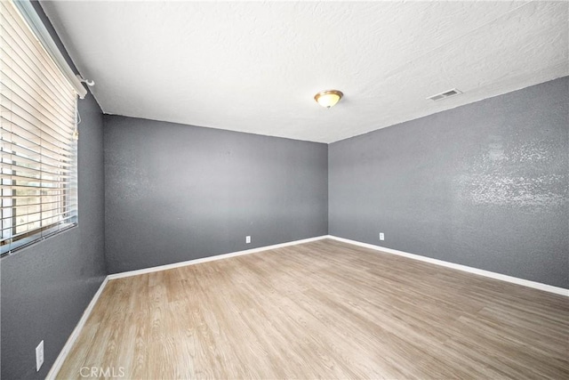 empty room with a textured ceiling and hardwood / wood-style flooring