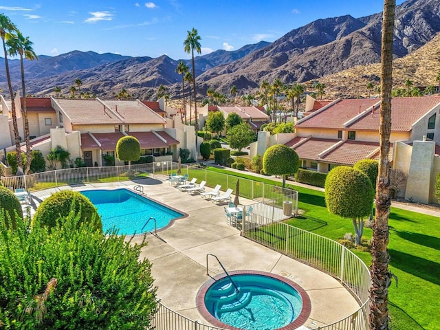 view of swimming pool with a hot tub, a patio, a mountain view, and a yard