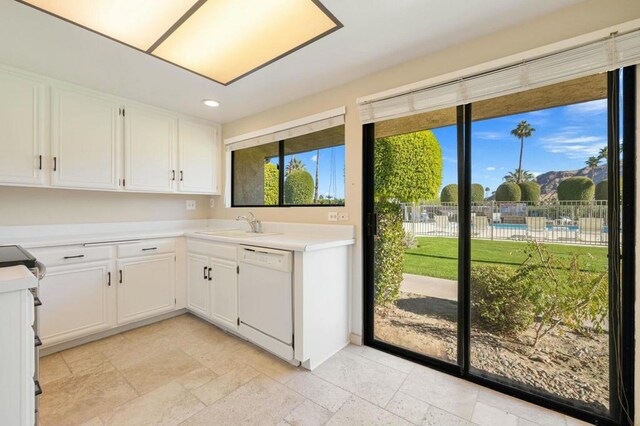 kitchen featuring sink, white dishwasher, and white cabinetry