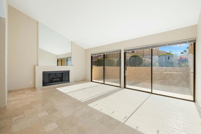 unfurnished living room with a brick fireplace and lofted ceiling