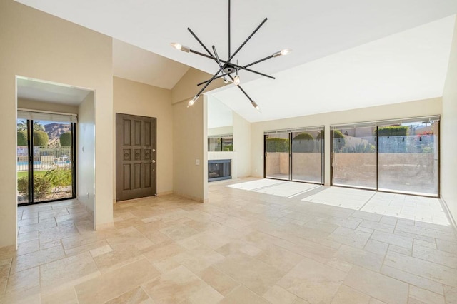 unfurnished living room featuring high vaulted ceiling and a notable chandelier