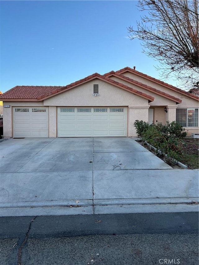 view of front of home with a garage, driveway, a tiled roof, and stucco siding